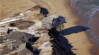 An aerial view of a building on pilings compromised by coastal erosion Truro, Mass.